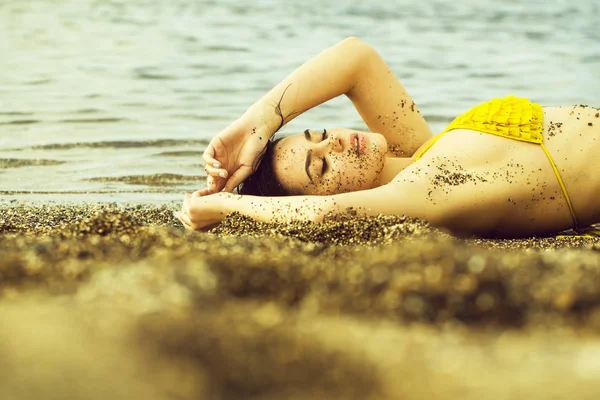 Menina bonita em maiô amarelo dormindo na praia do mar — Fotografia de Stock