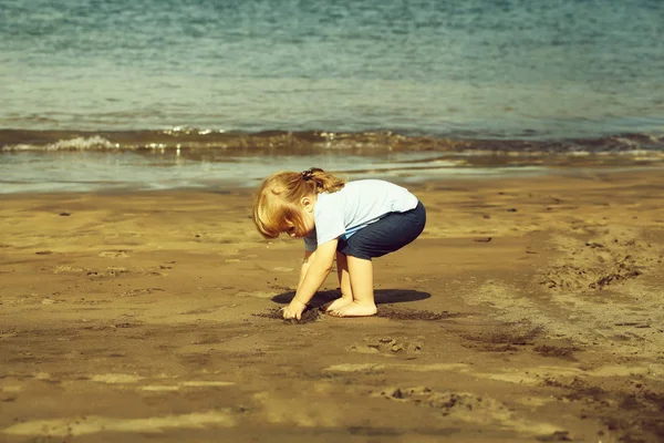 Carino bambino gioca con la sabbia sulla spiaggia di sabbia — Foto Stock