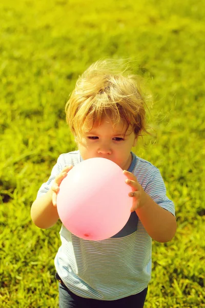 Menino brinca com balão de brinquedo rosa — Fotografia de Stock