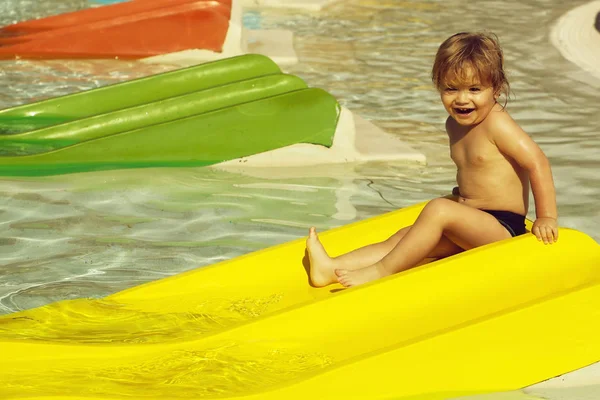 Feliz bebé lindo deslizándose desde el tobogán de agua amarillo —  Fotos de Stock