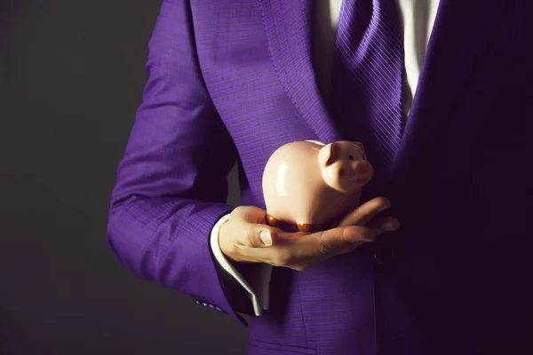 Piggy bank rosa para economizar dinheiro em pé na mão masculina — Fotografia de Stock