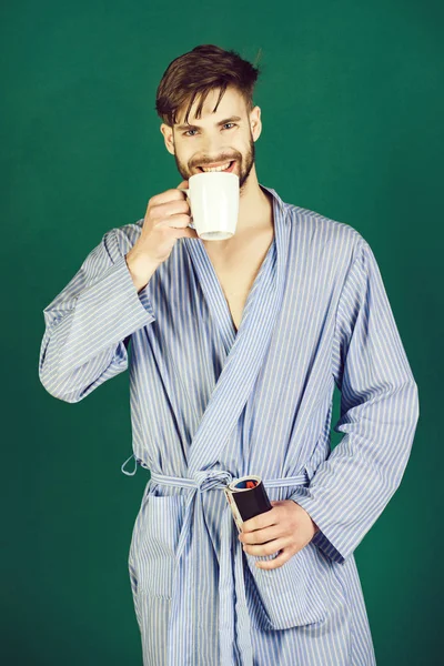 Утро человека, улыбающегося в синем халате с чашкой в руке — стоковое фото