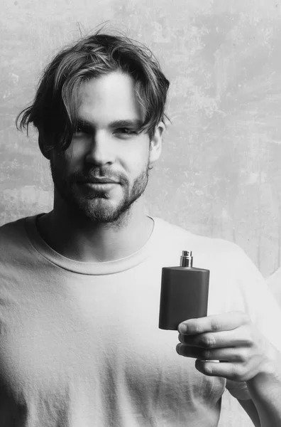 macho man posing with black perfume bottle