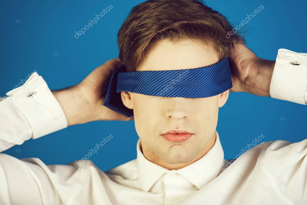 businessman blindfolded with tie on blue background