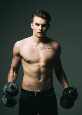 Kavram işe. Gövde, altı paketleri ile kas maço adam dambıl, koyu arka plan tutar. Dövme çekici adamla. Maço kas şekil, sporcu, vücut geliştirmeci ile kendine güvenen yüzünde.