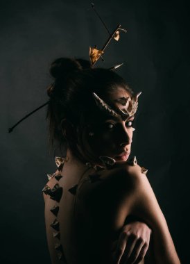 Cadılar Bayramı fikirler kavramı. Boynuzları ve dikenler fantezi yaratık olan kadın. Şeytani görünüm. Mistik Peri kuyruk karakter. Dikenler bir kızla şeytan ejderha büyülü yaratık olarak. Kız fantezi tarzı makyaj