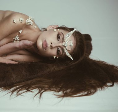 Boynuzları ve dikenleri olan bir şeytan. Cadılar Bayramı hayali yaratığı. Büyülü, korkunç dişi yaratık rahatlamış ışık arka planında uzanıyordu. Kadınlar cadılar bayramı kutlaması gibi barışır.