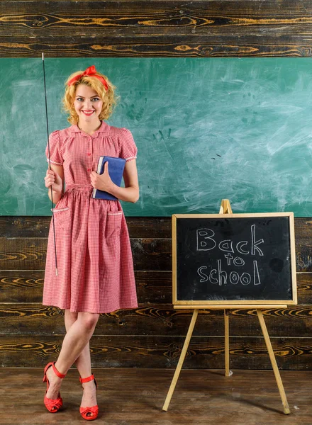Lehrer lächeln mit Buch und Zeiger im Klassenzimmer. zufriedene Lehrer zurück in die Schule über Tafel Hintergrund. Schön und genial — Stockfoto