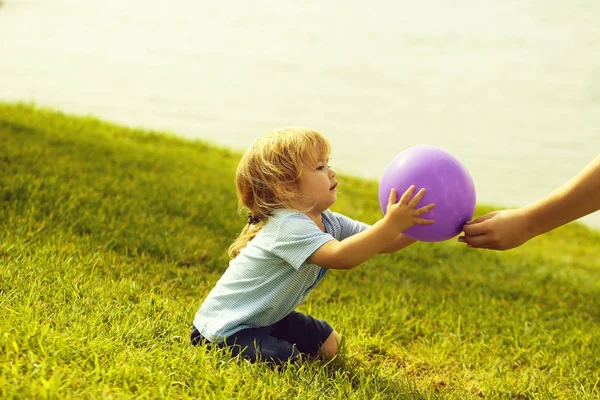 Cute baby boy catches violet toy balloon — Stock Photo, Image