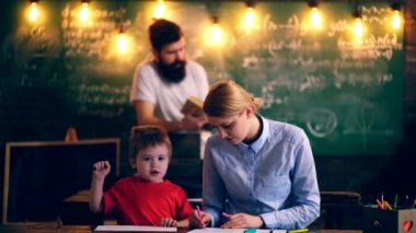 Anne ve oğlu okul tablosu çizip babası arka planda kitap okur. Öğrenme kavramı. Okul çocukları üniformalı. Öğretmen sınıfta.