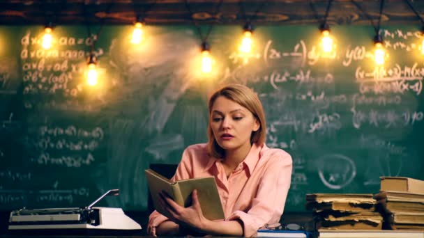 O professor está interessado em ler um livro em uma sala de aula da escola sobre um fundo de um conselho de escola verde. Professor na sala de aula. Professor e aluno. De volta à escola . — Vídeo de Stock