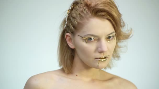 Ein Mädchen mit goldenem Make-up schaut genau hin. Erotik-Konzept. — Stockvideo