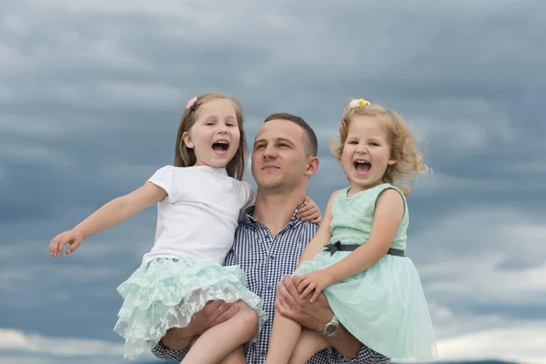 Vater hält Töchter am trüben grauen Himmel — Stockfoto