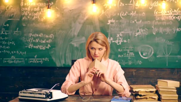 Am Tisch im Klassenzimmer liest die Lehrerin vor dem Hintergrund einer grünen Tafel ein Buch. Lernkonzept. Schulkinder in Uniform. Lehrer im Klassenzimmer. — Stockvideo