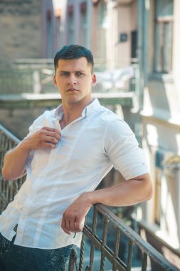 Yakışıklı genç adam balkon Küpeşte ayakta ve uzağa bakarak açık