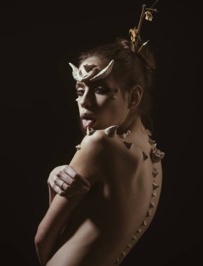 Boynuzları ve omuz pembe bir dili fantezi yaratık yalama dikenler olan kadın. Cazip karakter. Cadılar Bayramı makyaj. Dikenler bir kızla şeytan ejderha büyülü yaratık olarak. Kızla fantazi tarzı makyaj