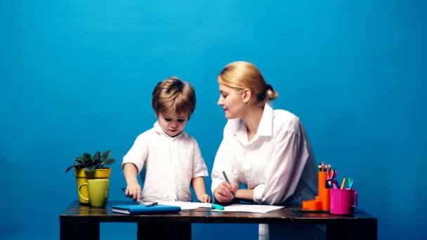 Mom and son painting together on a blue background. Concept of family communication. Mom and son have fun drawing time. — Stock Video