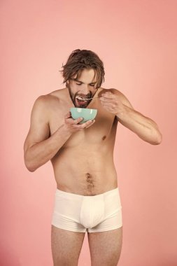 Islak saçlı adam yemek Kahvaltı, pembe arka plan.