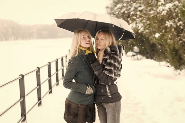 Två systrar leende under paraply vinterdag — Stockfoto