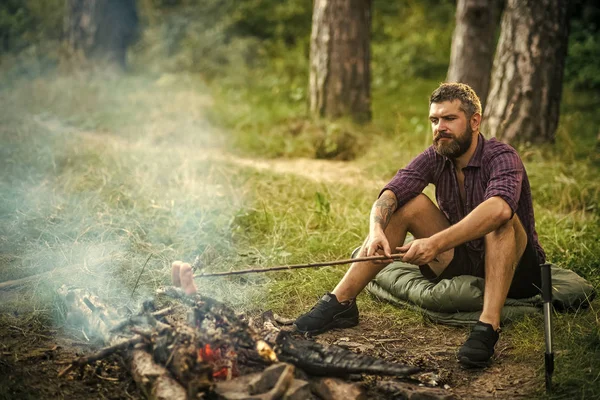 Homme randonneur rôti saucisses sur bâton sur le feu de joie dans la forêt — Photo