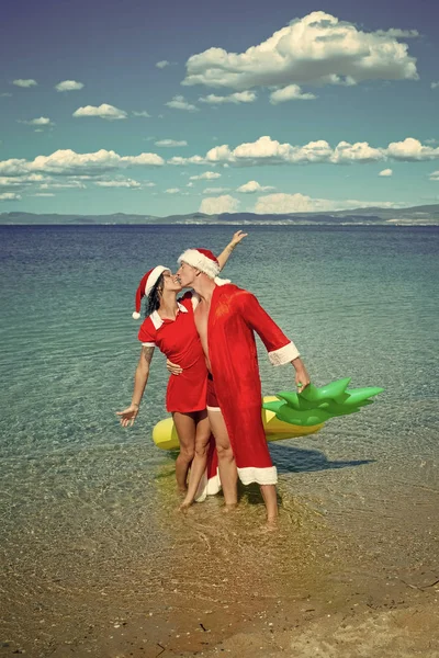 Verliebtes Weihnachtspaar als Weihnachtsmann im Strandwasser — Stockfoto
