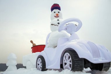 Kış günü karlı zemin üzerine beyaz gökyüzü üzerinde oyuncak araba sürüş kardan adam. Noel ve yeni yıl. Tatil kutlama kavramı