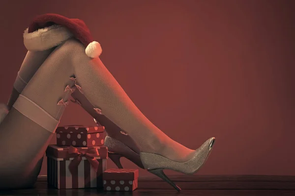 Новорічні ноги на червоному тлі з подарунком . — стокове фото
