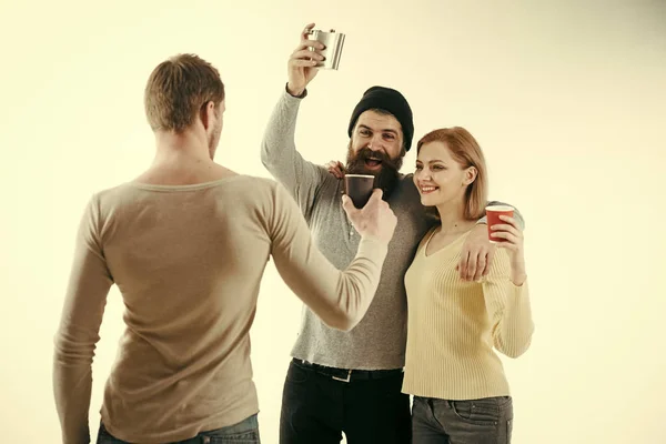 Glada vänners tillbringar fritid med drycker. Killar håller cup, kolv med alkohol, talar. Män, kvinna på leende ansikten, vit bakgrund. Nöje och fritid koncept. Kommunikation, vänskap, kul. — Stockfoto