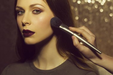 Profesyonel makyöz güzel genç bir kadınla çalışıyor.