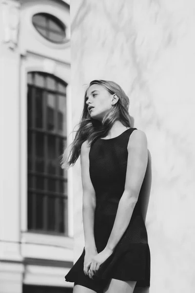 Menina bonita em vestido preto na moda na parede do edifício — Fotografia de Stock