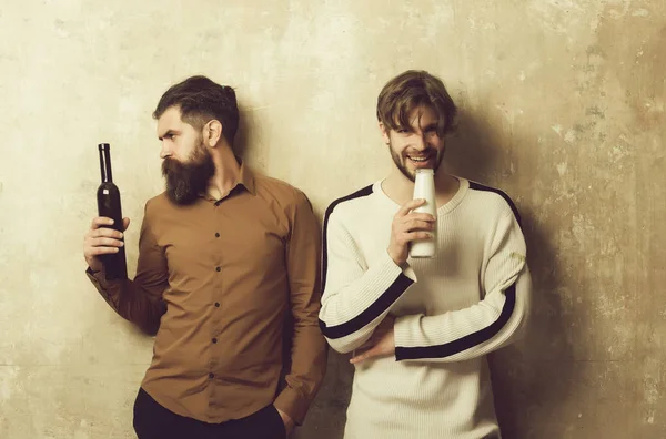 Hombre serio con botella de vino y modelo feliz con leche — Foto de Stock