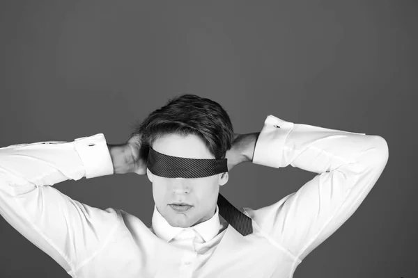 tie on face and eyes of young blindfolded man, businessman