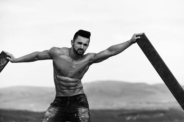 Mannen med muskulös kropp utbildning på rostiga järn stång — Stockfoto