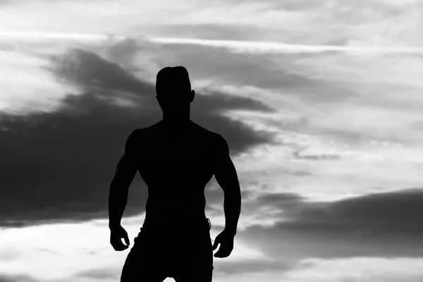 青い空に筋肉のついた体でセクシーな男の siolhouette — ストック写真