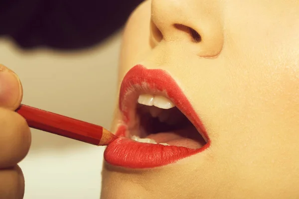 Lippen krijgen rood potlood make-up door mannenhand — Stockfoto