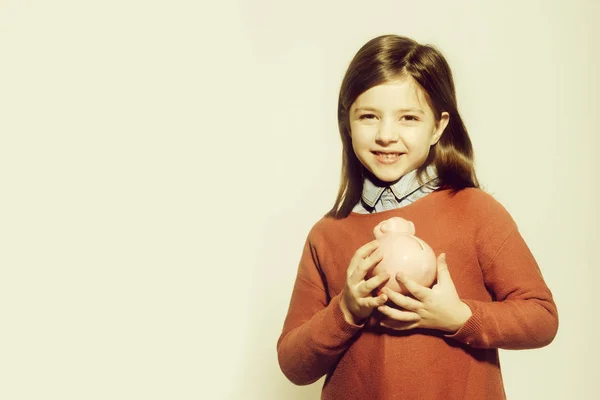 Sparschwein in den Händen eines kleinen Mädchens, das lächelt — Stockfoto