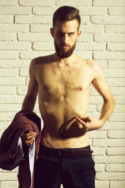 slim bearded man with thin bare torso on brick background