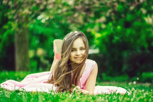 花びらと緑の草の上の少女 — ストック写真
