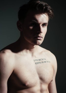 Gövde, kas maço, gölge beden, koyu arka plan üzerinde olan adam. Adam dövme ile kendinden emin ve çekici görünüyor. Seksi maço kavramı. Maço kas şekil, sporcu, vücut geliştirmeci dalgın yüzünde.