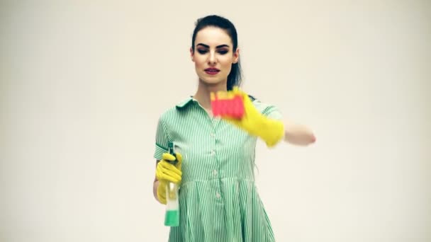 Mujer con guantes sonriendo y limpiando polvo usando un spray y un plumero. Concepto de limpieza con suministros. Hermosa joven mujer hace limpieza. Hermosa mujer en guantes de limpieza . — Vídeo de stock