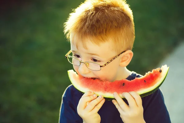 Gelukkige jongen met rood haar in glazen eten van watermeloen — Stockfoto