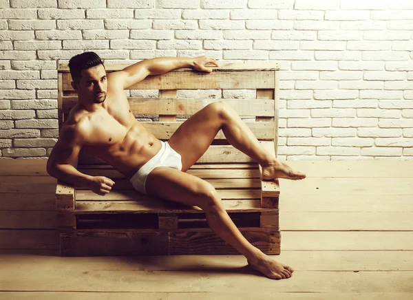 Hombre musculoso guapo en banco de madera —  Fotos de Stock
