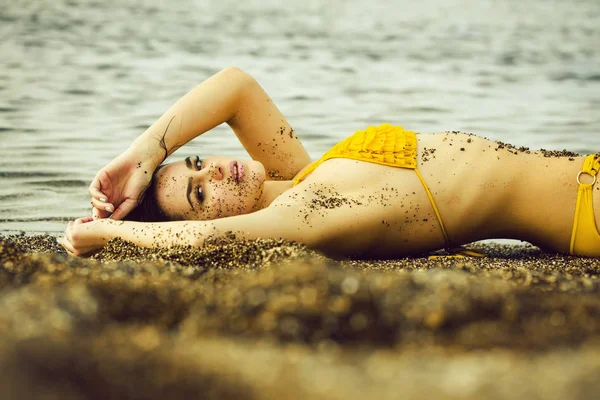Söt flicka i gul baddräkt sovande på stranden — Stockfoto