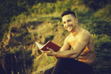 Kitap açık ile gülümseyen kaslı adam