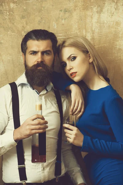 Frau und Mann posieren mit Flasche und Glas Likör — Stockfoto
