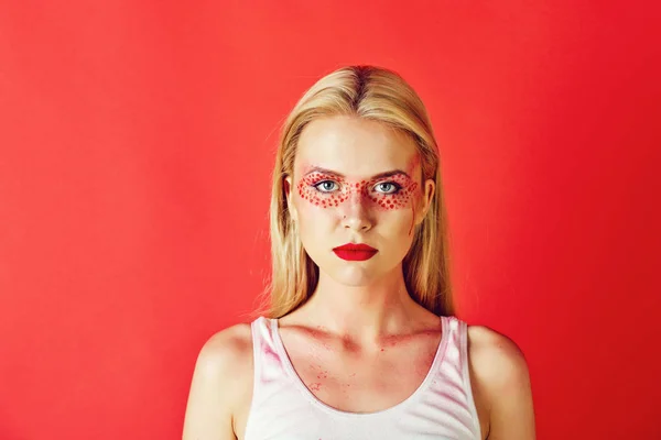 Bonita mujer rubia con maquillaje creativo de moda sobre fondo rojo —  Fotos de Stock