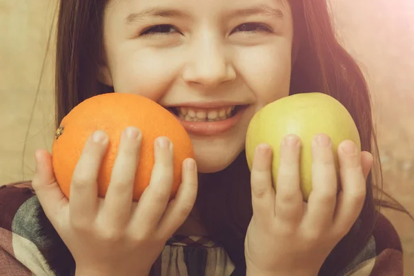 Menina feliz segurando laranja e maçã nas mãos — Fotografia de Stock