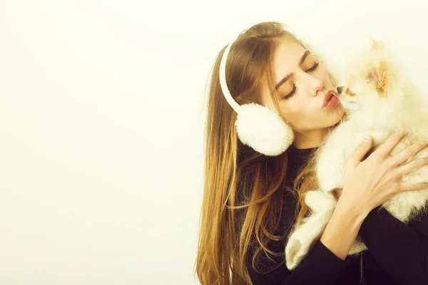 Sexy bonita menina beijando pequeno pomeranian cão em earmuffs — Fotografia de Stock