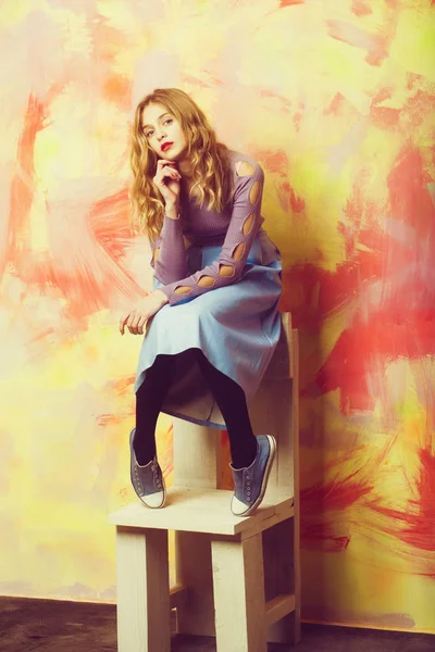 Menina bonita em saia azul e tênis na cadeira de madeira — Fotografia de Stock