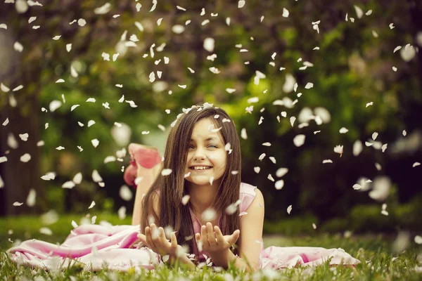 Yaprakları yeşil çimenlerin üzerinde küçük kız